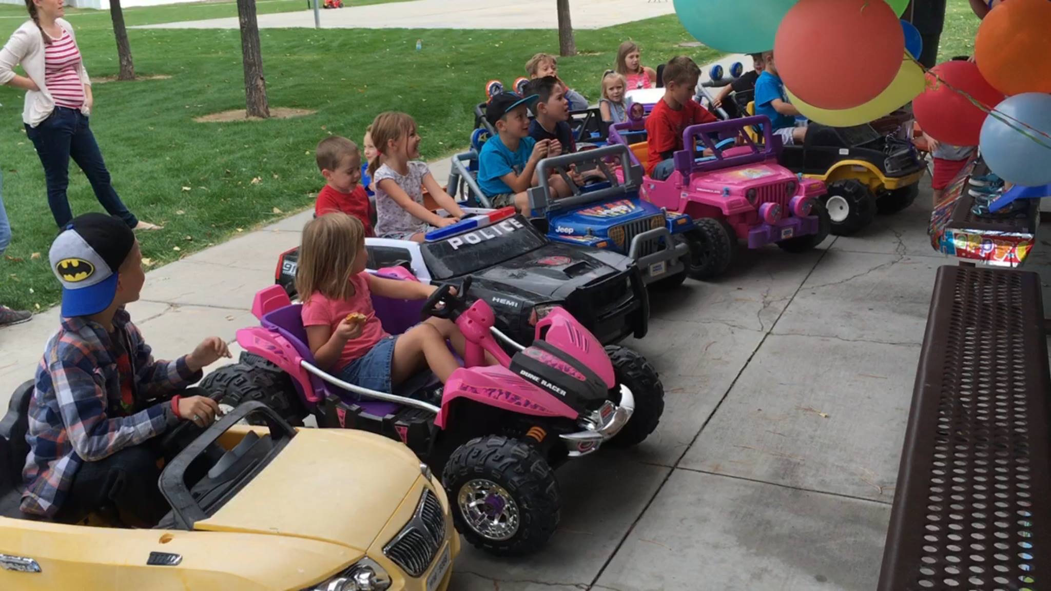 Kids lined up in Power Wheels cars at a party