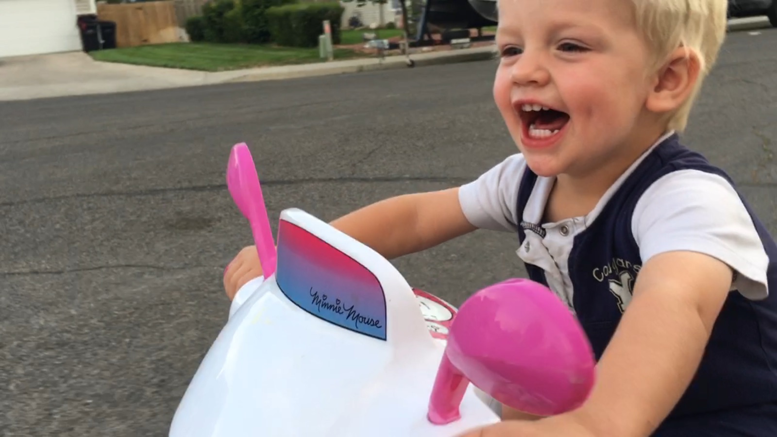 Toddler laughing while driving a Power Wheels car